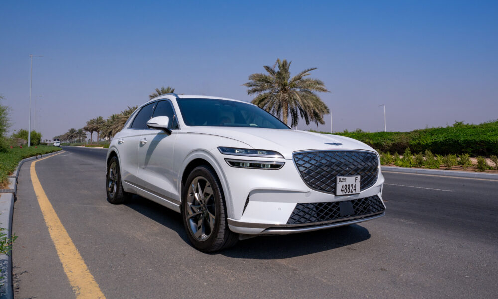 A front-three-quarter-shot of a white 2025 Genesis Electrified GV70 parked on the roadside.