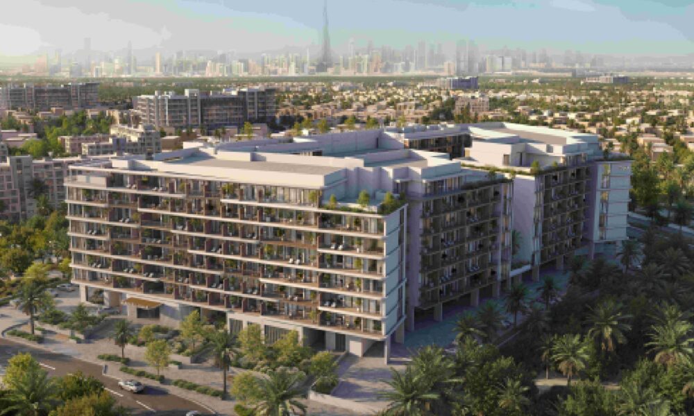 Aerial view of Ashley Hills residential development in Arjan, Dubai, showing modern apartment buildings surrounded by green landscaping with Dubai skyline in background.