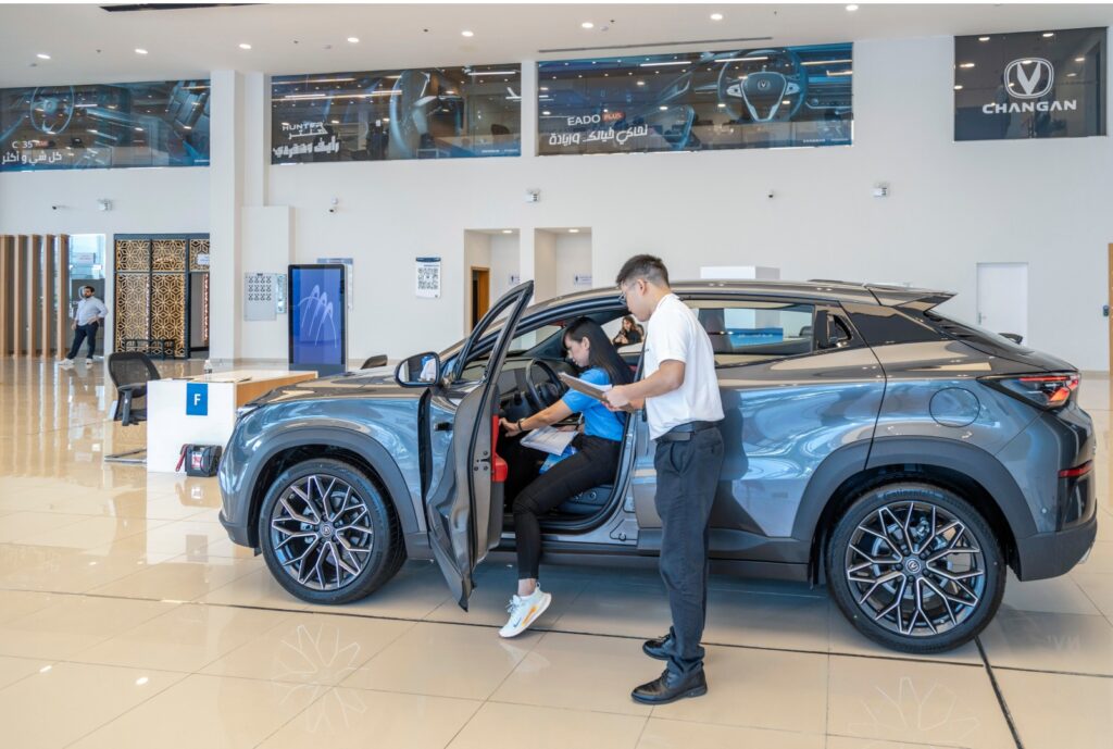 a side-angle shot of an automotive professional inside a car with a product manual