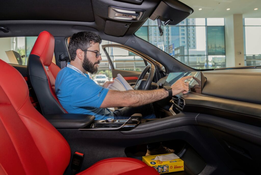 a side-angle shot of an automotive professional inside a car with a product manual