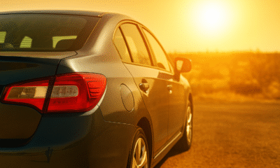 Metallic dark blue sedan parked on an urban street under bright sunlight, representing summer vehicle safety.