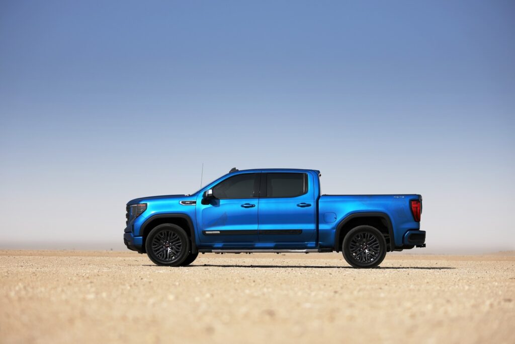 A side-angle shot of a GMC truck parked in the desert.