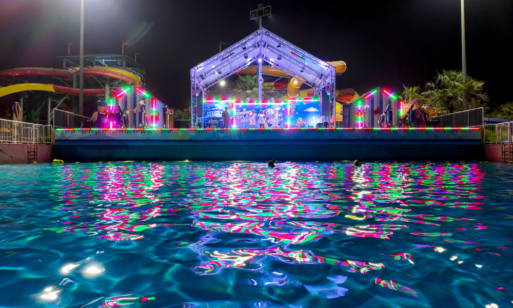 LEGOLAND Dubai Water Park’s Neon Nights event with a glowing stage, vibrant neon lights reflecting on the wave pool, and themed LEGO decorations.