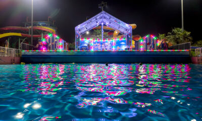 LEGOLAND Dubai Water Park’s Neon Nights event with a glowing stage, vibrant neon lights reflecting on the wave pool, and themed LEGO decorations.