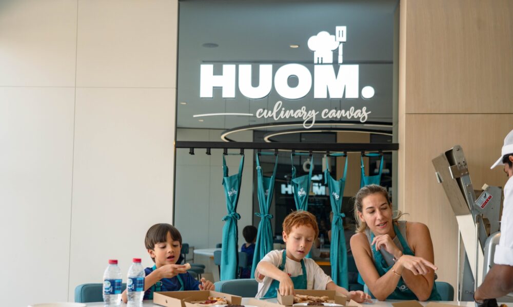 Mother and two children cooking together at HUOM Culinary Canvas cooking studio with chef instructor in modern kitchen setting.