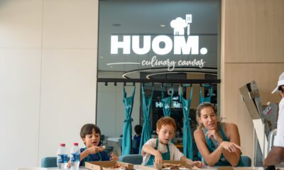 Mother and two children cooking together at HUOM Culinary Canvas cooking studio with chef instructor in modern kitchen setting.