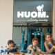 Mother and two children cooking together at HUOM Culinary Canvas cooking studio with chef instructor in modern kitchen setting.