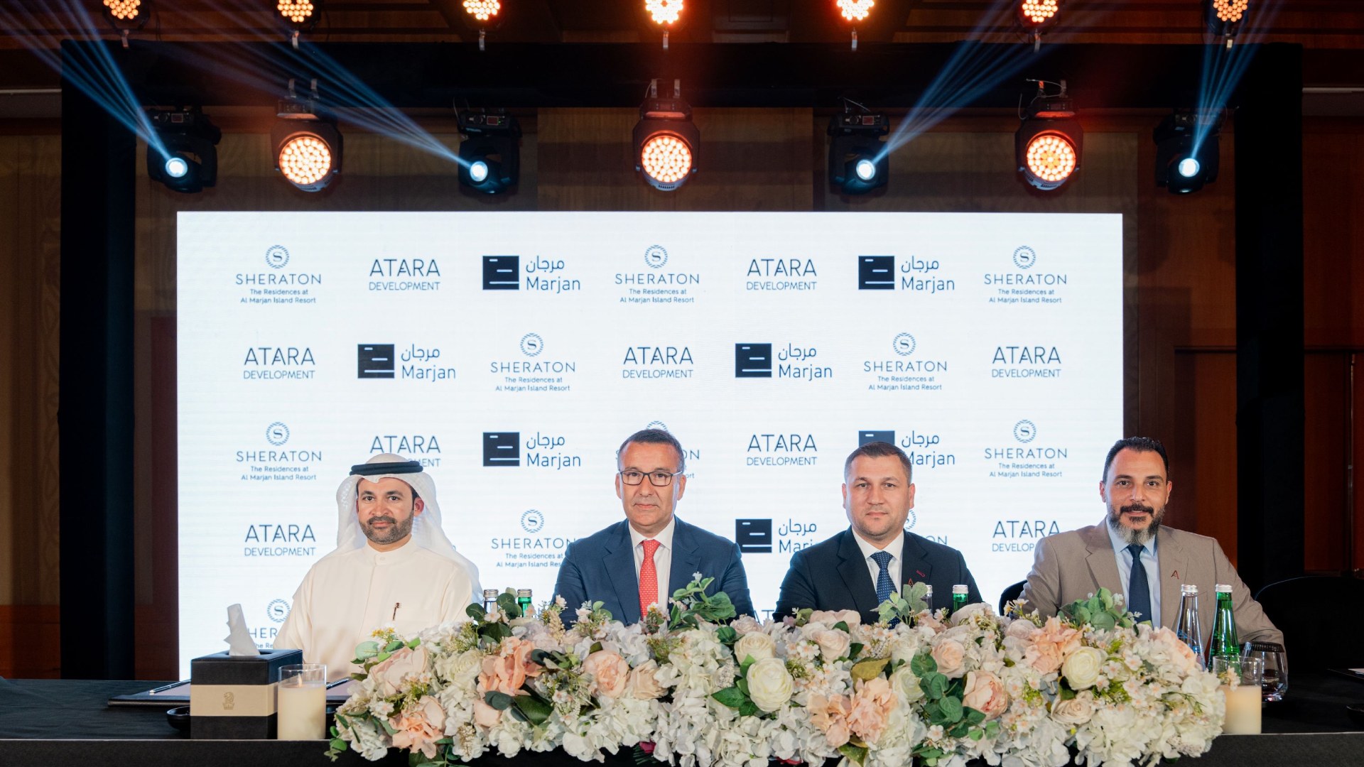 Four executives at ATARA Development, Sheraton, and Marjan partnership signing ceremony with floral arrangements and branded backdrop wall.