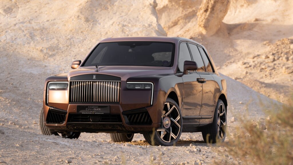 A front three-quarter shot of the Rolls-Royce Black Badge Cullinan Series II Desert Sunset parked in the desert.