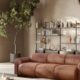 Natuzzi Italia terracotta leather sofa in Mediterranean-inspired living space with curved architecture, indoor olive tree, and modern shelving unit.