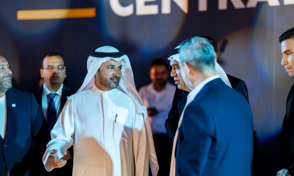 Group of business leaders in formal attire conversing at an event, with one man in traditional Emirati dress at the center