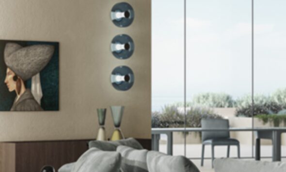 Modern living room interior with wall art, decorative lighting fixtures, glass vases, and large windows overlooking greenery.