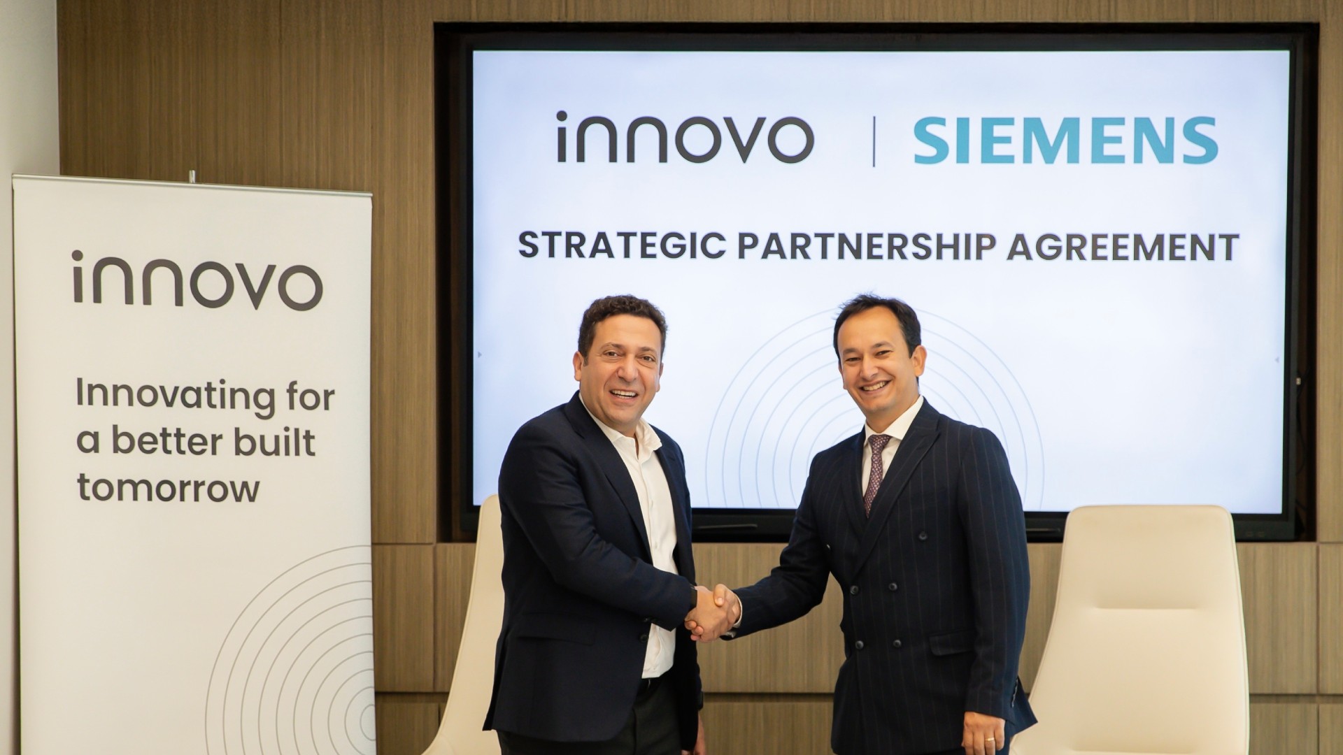 Two executives from Innovo and Siemens shake hands during a strategic partnership agreement signing ceremony in Dubai.