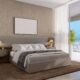 Modern master bedroom with contemporary Pininfarina furniture, textured wall panels, panoramic city views, and neutral color scheme in luxury Dubai apartment.