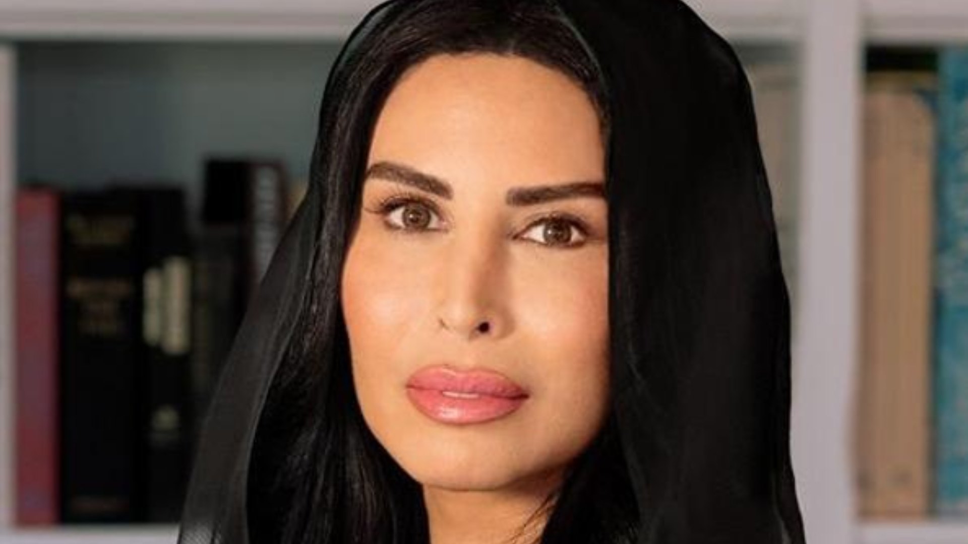 Rasha Al Mubarak, Founder and Chairwoman of Music Nation, portrait in black abaya against modern office interior background.