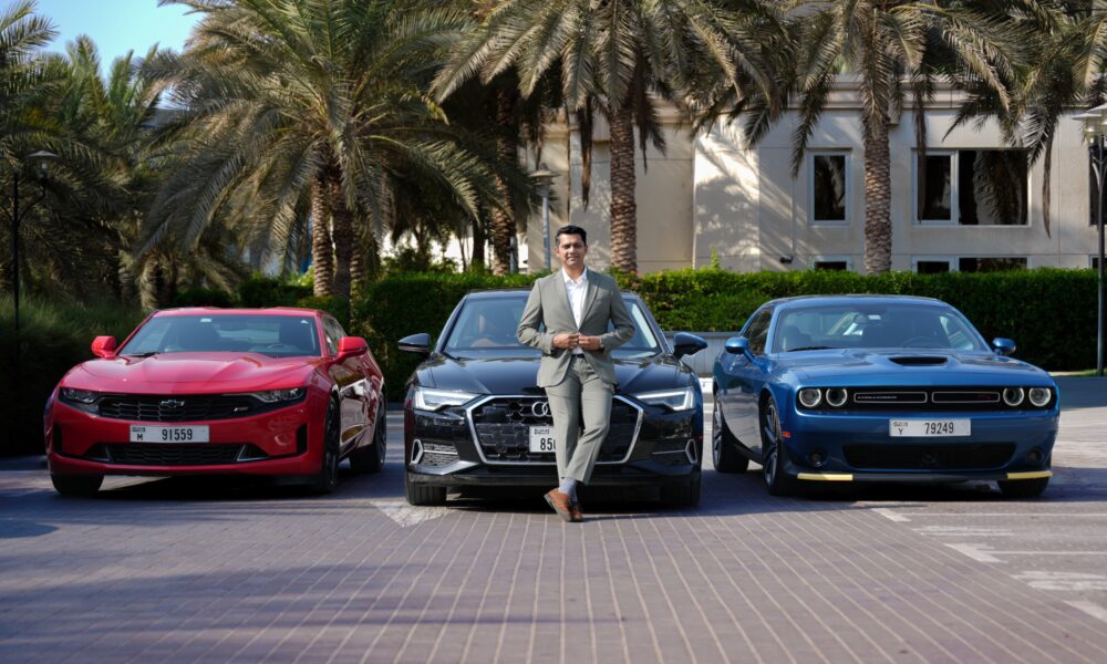 A front-angle shot of Harshvardhan Singh, Business Head, CARIVA standing in front of an Audi A6, Chevy Camaro and Dodge Charger
