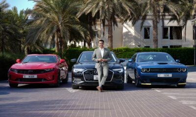 A front-angle shot of Harshvardhan Singh, Business Head, CARIVA standing in front of an Audi A6, Chevy Camaro and Dodge Charger