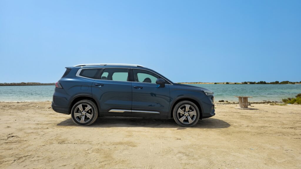 A sde-angle shot of a blue Geely Okavango parked outdoors.