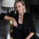 Professional portrait of Olga Pankina, Whitewill Dubai COO, wearing black blazer and seated beside gray velvet chair with gold accents in contemporary office interior