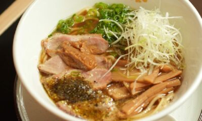Bowl of ramen noodle soup with sliced pork, green onions, bamboo shoots, and shredded white radish in savory broth