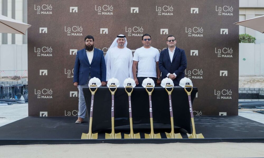 Four executives at MAAIA La Clé groundbreaking event with ceremonial shovels and hard hats at Al Furjan construction site.