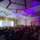 Large audience at Synology UAE Solution Day event with speaker presenting enterprise data protection solutions on stage with purple ambient lighting.