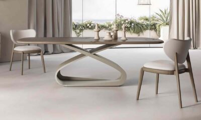 Modern dining room with a sculptural oval table, two upholstered chairs, and neutral-toned minimalist decor