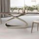 Modern dining room with a sculptural oval table, two upholstered chairs, and neutral-toned minimalist decor