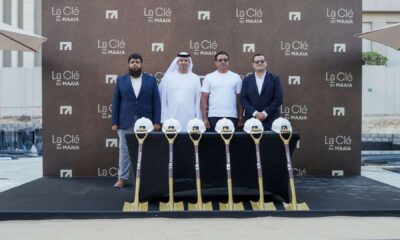Four executives at MAAIA La Clé groundbreaking event with ceremonial shovels and hard hats at Al Furjan construction site.