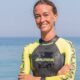 Alessia Zecchini, world champion freediver, in yellow and black wetsuit smiling by the ocean before diving event at Sun Siyam Olhuveli.