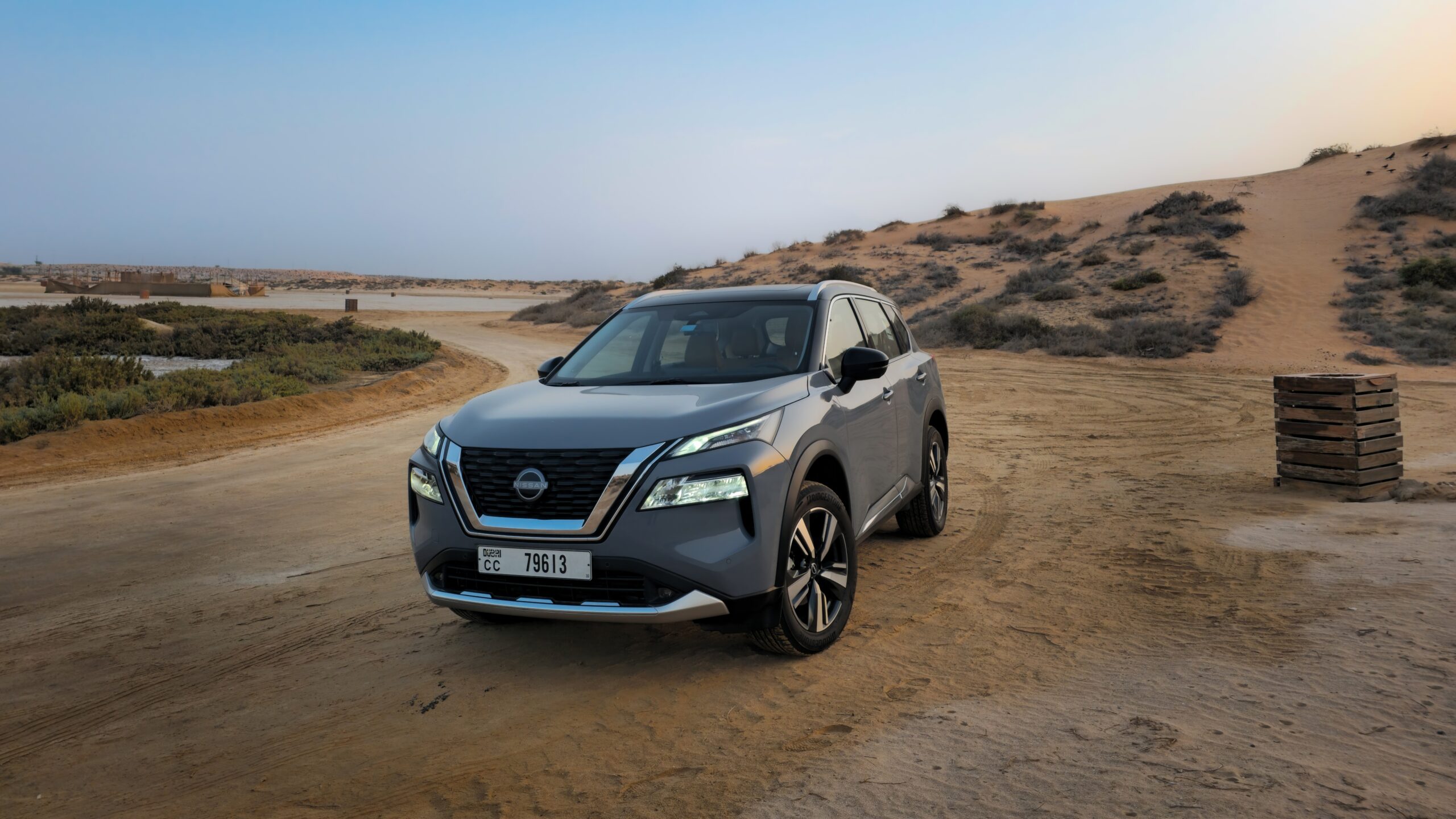 A front-angle three-quarter shot of a Gray 2025 Nissan X-Trail parked outdoors in a desert.