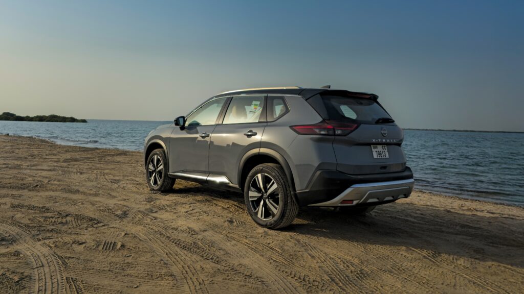A rear-angle three-quarter shot of a Gray 2025 Nissan X-Trail parked outdoors in a desert.