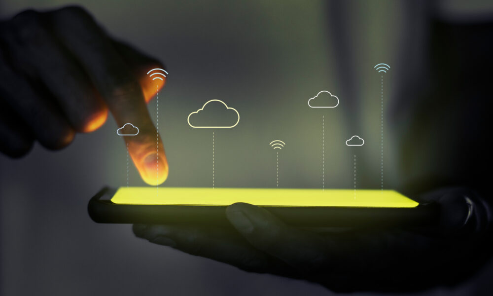 A visualization of cloud platforms portrayed by a mobile screen touched by the person holding it while abstract cloud icons are floating above it,