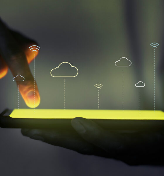 A visualization of cloud platforms portrayed by a mobile screen touched by the person holding it while abstract cloud icons are floating above it,