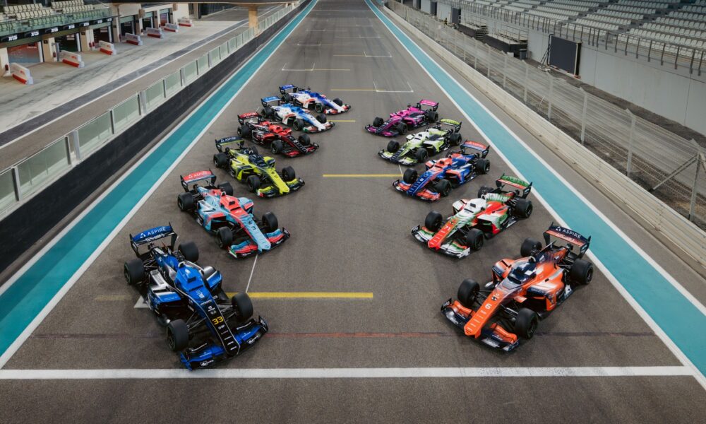 A top-wide-angle shot of all the A2RL race cars parked in formation on the race track.