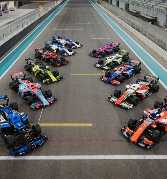 A top-wide-angle shot of all the A2RL race cars parked in formation on the race track.