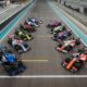 A top-wide-angle shot of all the A2RL race cars parked in formation on the race track.