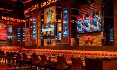 Tiger Bar Stock Exchange interior with neon signs, orange leather seating, sports memorabilia, and multiple screens at Barceló Al Jaddaf