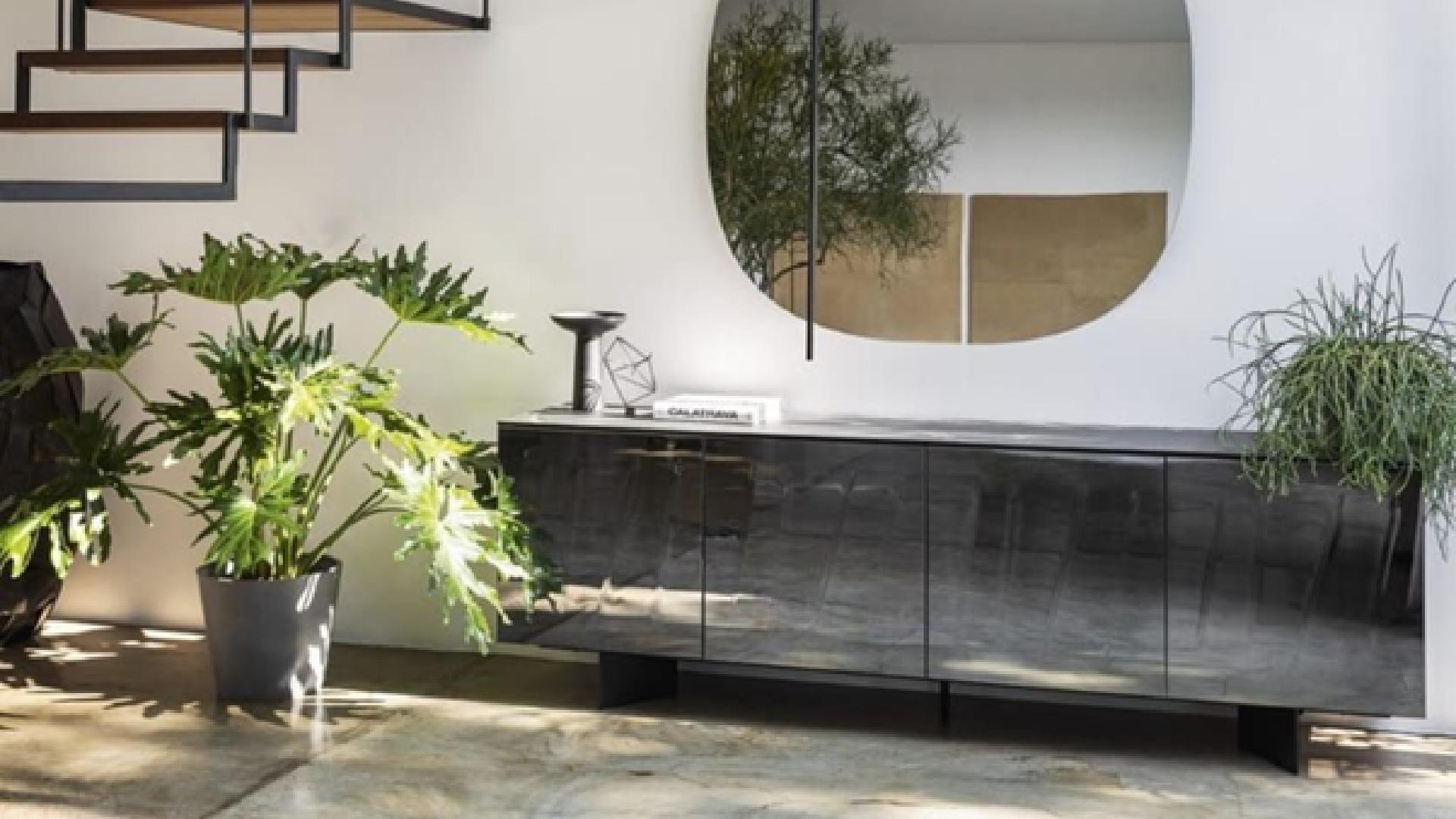 A luxurious, light-filled living room features a modular, pale beige sofa, a low wooden coffee table with books and decor, and a soft, patterned area rug, emphasizing comfort and minimalist Italian design.