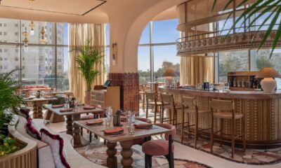 SO/ Ras Al Khaimah restaurant interior featuring warm earth tones, decorative bar area, and floor-to-ceiling windows with natural light