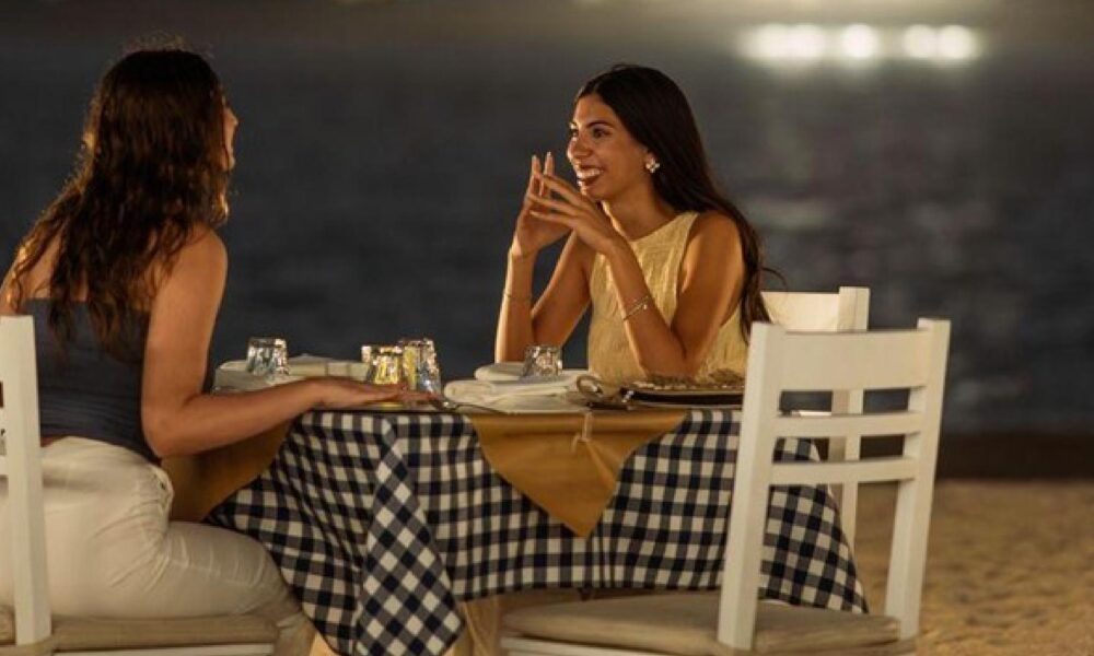 Two people sitting on the beach and resting and laughing and talking
