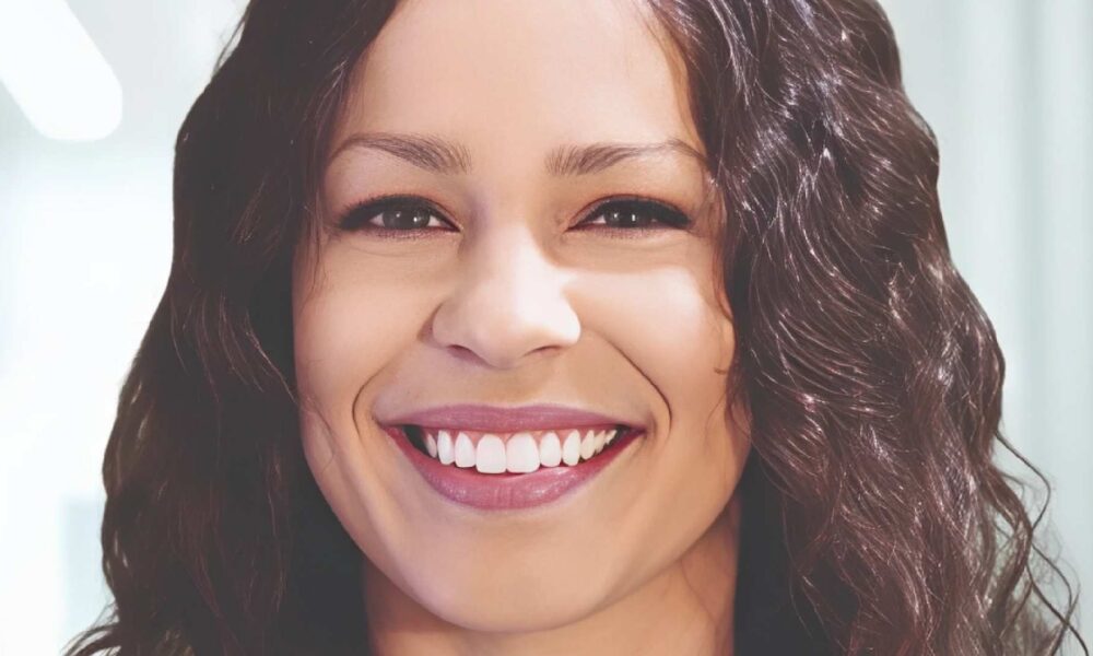 Professional headshot of smiling woman with wavy brown hair