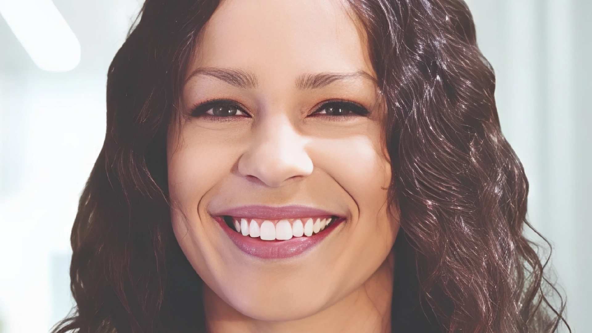 Professional headshot of smiling woman with wavy brown hair