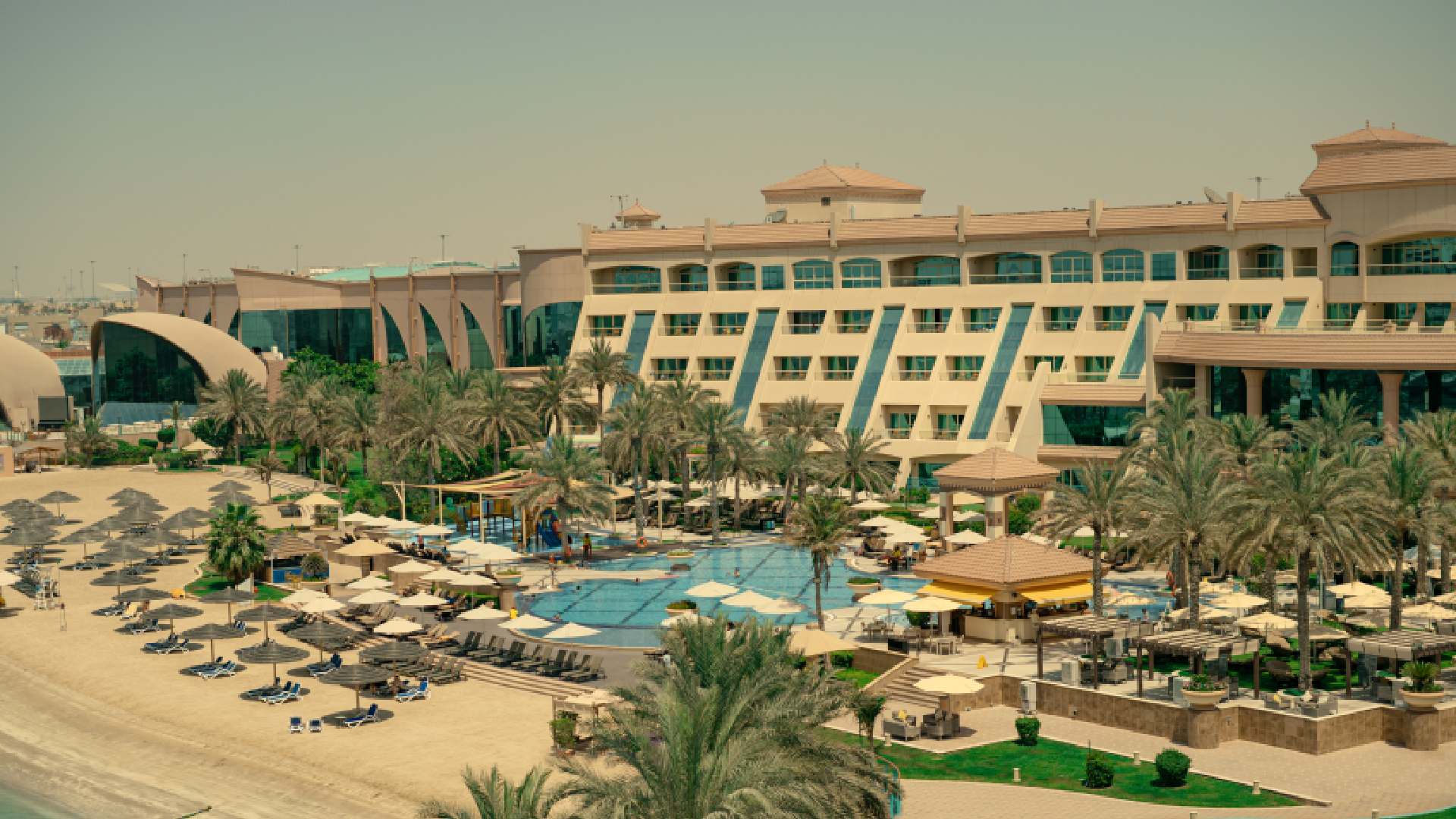 Al Raha Beach Resort & Spa beachfront property with swimming pool, sun loungers, palm trees, and resort facilities