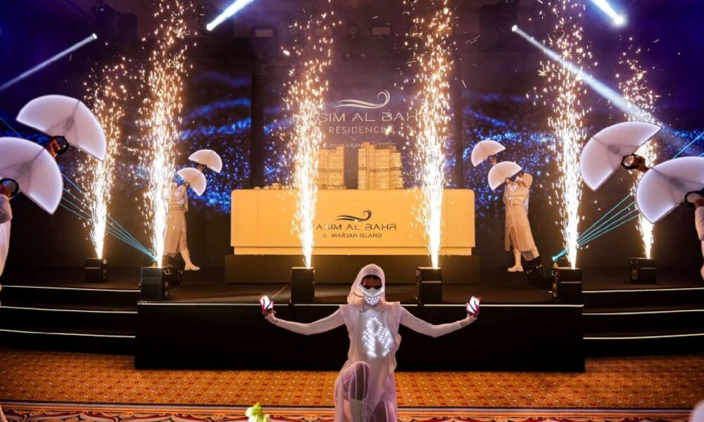 Marjan Island launch event with pyrotechnics, performers in traditional dress, and Ajm Al Bahr Residences branding on stage