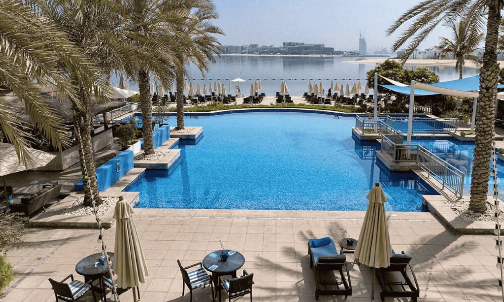 Luxury hotel pool with palm trees overlooking Dubai skyline and waterfront