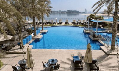 Luxury hotel pool with palm trees overlooking Dubai skyline and waterfront
