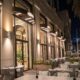 "Luxury outdoor dining terrace at night with modern architecture, ambient lighting, white seating, and illuminated palm trees in Dubai