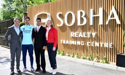 Four professionals standing in front of Sobha Realty Training Centre wooden signage with greenery