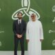 Two business professionals pose at a corporate event with green branded backdrop featuring Metropolitan, Manarah Group, and Leaf Tower logos